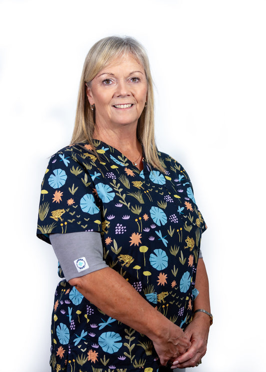 Smiling middle-aged nurse wearing grey marle Under Snugs under pretty navy & blue floral patterned scrubs