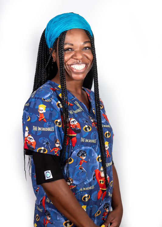 Happy, smiling nurse with long braids & a head scarf wearing black Under Snugs under colourful blue scrubs feturing 'The Incredibles'