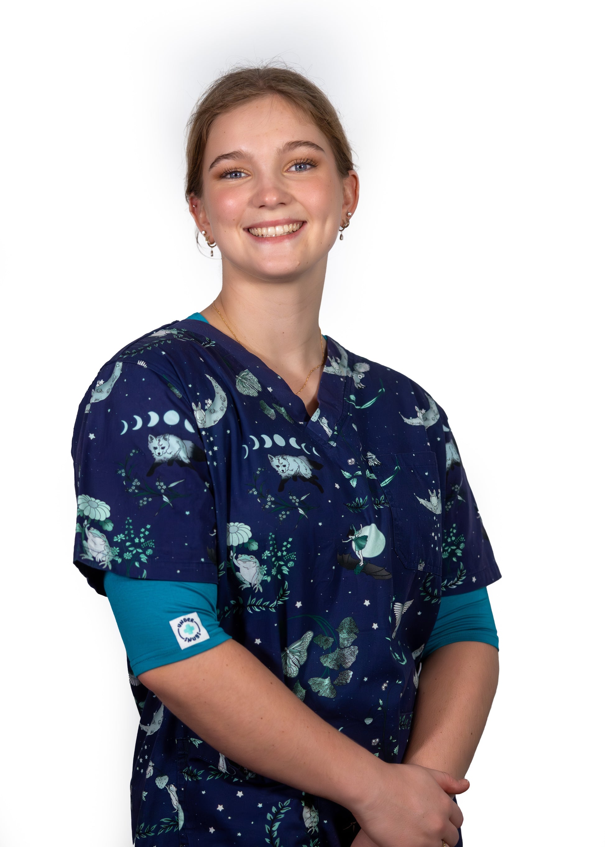 Young nurse smiling whilst wearing peacock coloured Under Snugs under her navy scrubs which feature cute animals, stars & moons