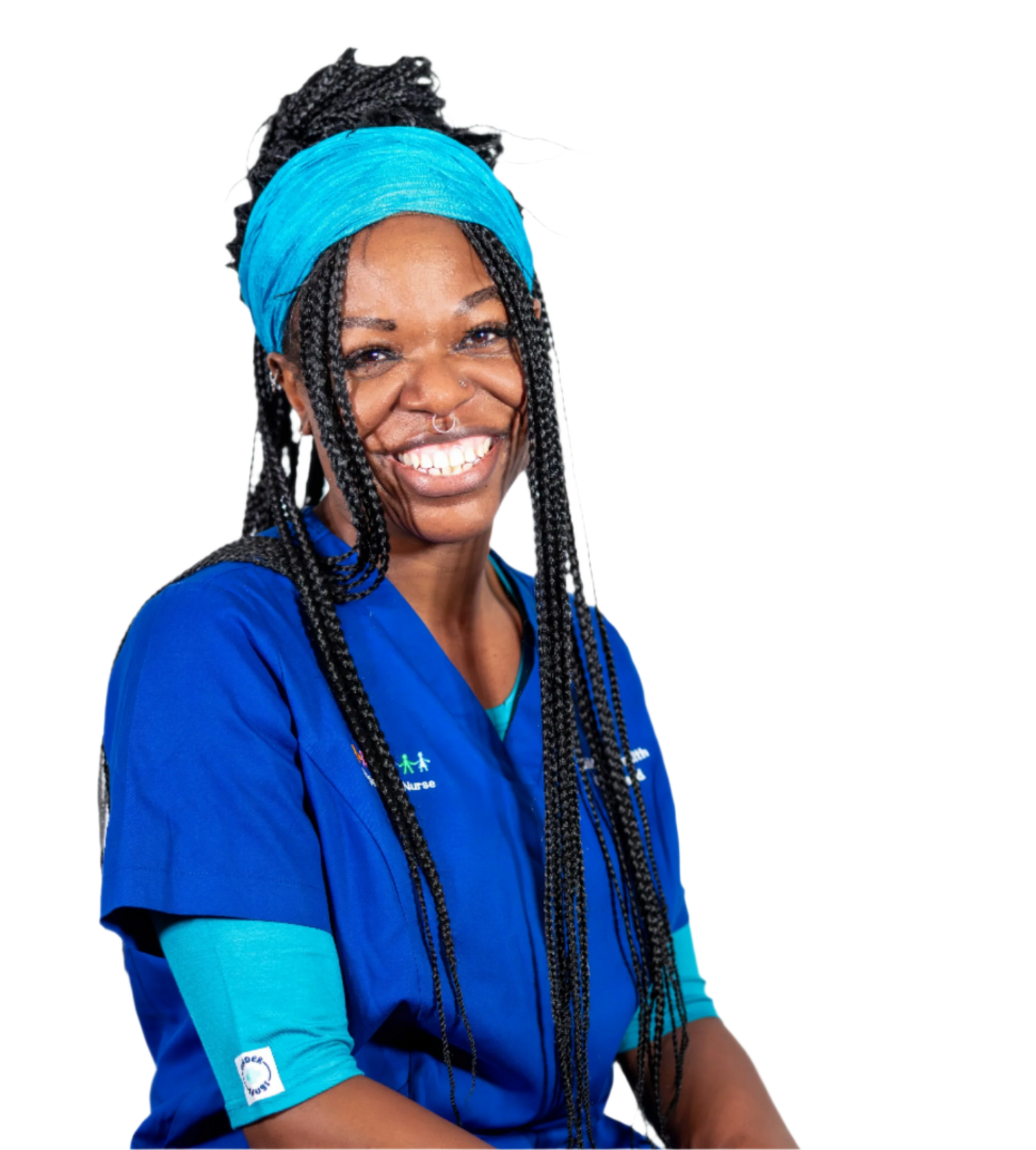 Young nurse with long braids & a peacock coloured head scarf with a big smile, wearing peacock Under Snugs under bright blue hospital scrubs