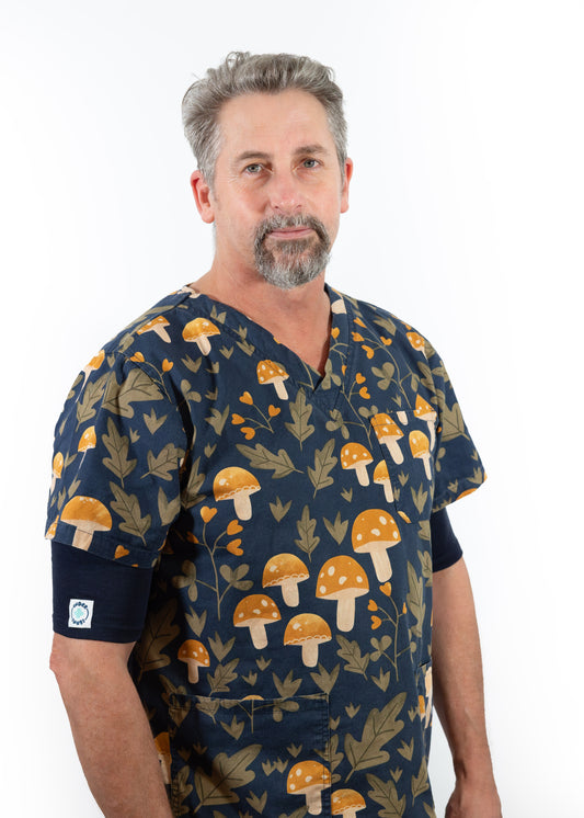 Smiling middle aged nurse wearing navy blue Under Snugs under his navy blue scrubs which feature a yellow & green mushroom & flower pattern
