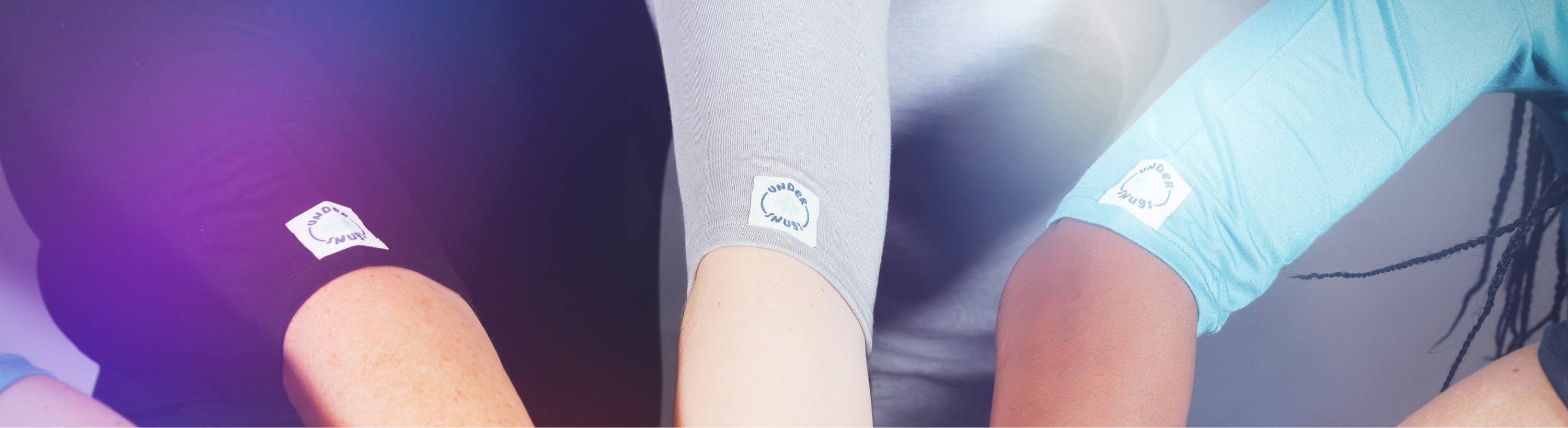 Photo showing a group of different peoples arms wearing different coloured Under Snugs, with the Under Snugs logo in view